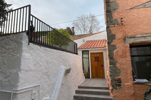 A staircase leading to a wooden door, with a white wall and a black railing on the left. - Valentinos House & Pool, Costa Maresme – 20 mins from Barcelona (Vilassar de Dalt)