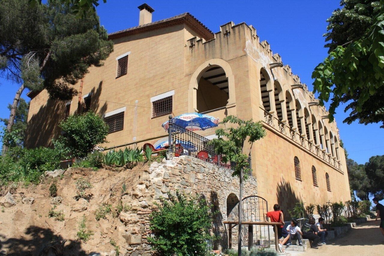 Um edifício histórico com janelas em arco e uma escadaria de pedra que leva à entrada.
