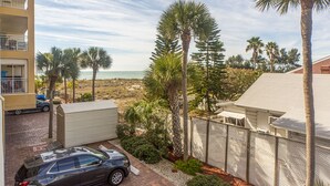 Un quartier résidentiel avec vue sur la plage, une voiture garée et un immeuble doté d’un balcon.