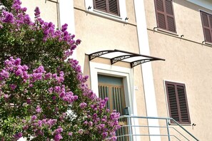 Un bâtiment doté d’un balcon, d’une porte et de volets.