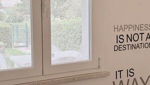 A room with a window, a wall with text, and a view of greenery outside. - M272 - Marcelli, new three-room apartment with garden (Marcelli)