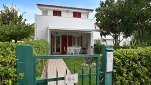 A white building with red shutters, a gated entrance, and a number 64 sign. - M272 - Marcelli, new three-room apartment with garden (Marcelli)