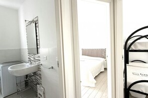 Ein Hotelzimmer mit Waschbecken, Spiegel und Bett mit weißer Bettwäsche.