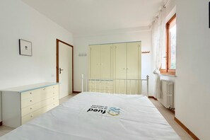 Un dormitorio con cama, armario, radiador y ventana.