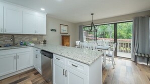A modern kitchen with white cabinetry, a granite countertop, and a dishwasher. - Fairway Villa 503 at Rumbling Bald (Lake Lure)