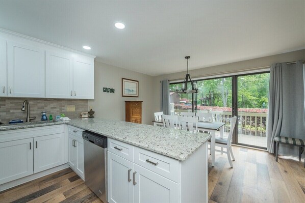 A modern kitchen with white cabinetry, a granite countertop, and a dishwasher.