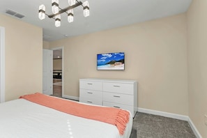 Une chambre à coucher avec un lit, une commode, un placard et un tableau au mur.