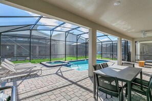 A covered patio area with a pool, outdoor furniture, and a view of a residential building. - Incredible 9BR! Private Pool+Theme Rooms+Game Room (Kissimmee)