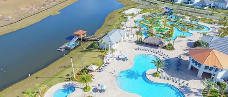 A resort with multiple swimming pools, a dock, and a view of the surrounding residential area.