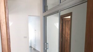 Een gang met een glazen deur en een houten deur, die leidt naar een andere kamer.