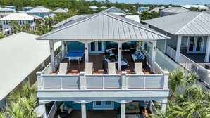 Ein zweistöckiges Haus mit einer überdachten Terrasse, die Gartenmöbel und einen Billardtisch bietet.