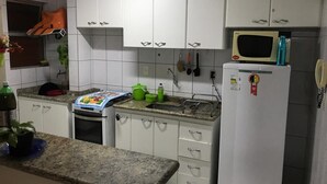 A kitchen with white cabinets, a microwave, a refrigerator, and a small oven. - Millennium Thermas Residence TOP (Caldas Novas)