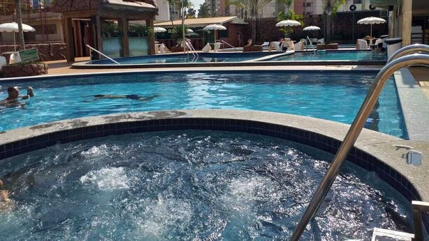 A swimming pool with a hot tub, lounge chairs, and umbrellas. - Millennium Thermas Residence TOP (Caldas Novas)