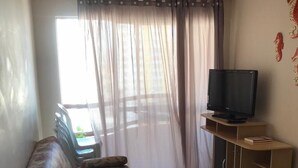 A living room with a floral sofa, a television on a wooden stand, and a ceiling fan. - Millennium Thermas Residence TOP (Caldas Novas)