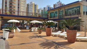 A rooftop pool area with lounge chairs, umbrellas, and potted plants. - Millennium Thermas Residence TOP (Caldas Novas)
