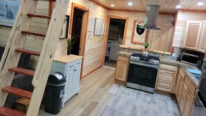 Ein Holzblockhaus-Innenraum mit Küche, Treppe und einer kleinen Essecke.