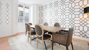 A dining area with a wooden table and chairs, a patterned wall, and a view of a balcony. - Genteel Home Madrazo IV Terrace (Madrid)