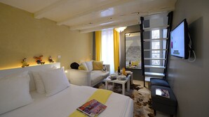 A hotel room with a bed, a sofa, a small table with a bottle and glasses, a TV mounted on the wall, and a window with curtains. - C3D Greenery (París)