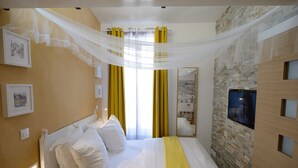 A hotel room with a bed, a large window with yellow curtains, a stone wall, and a television. - B4DD Opportunity (París)