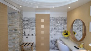 A modern bathroom with a stone accent wall, a large mirror, and a bathtub. - B4DD Opportunity (París)