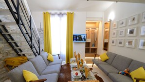 A modern living room with two grey sofas, yellow cushions, a wooden coffee table with a bottle, a small plant, and a framed picture on the wall. - B4DD Opportunity (París)