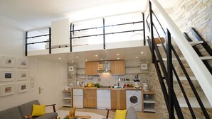 A compact living space with a kitchen, dining area, and a staircase leading to an upper level. - B4DD Opportunity (París)