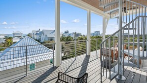 Un balcon spacieux avec une terrasse en bois, un escalier en colimaçon et une vue sur les bâtiments environnants.