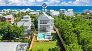 Un quartier résidentiel situé sur la côte, avec une grande maison blanche dotée d’une piscine et offrant une vue sur l’océan.