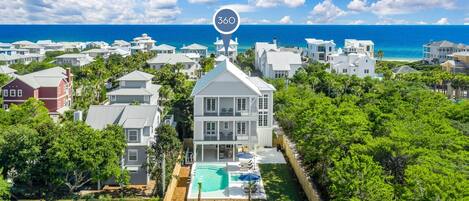 A coastal residential area with a large white house featuring a swimming pool and a view of the ocean.