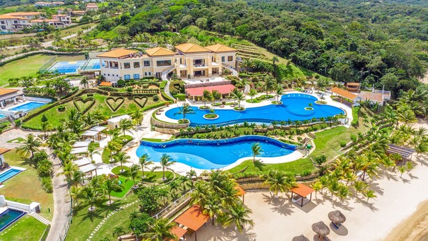 A resort with multiple swimming pools, palm trees, and a large building with a red roof.