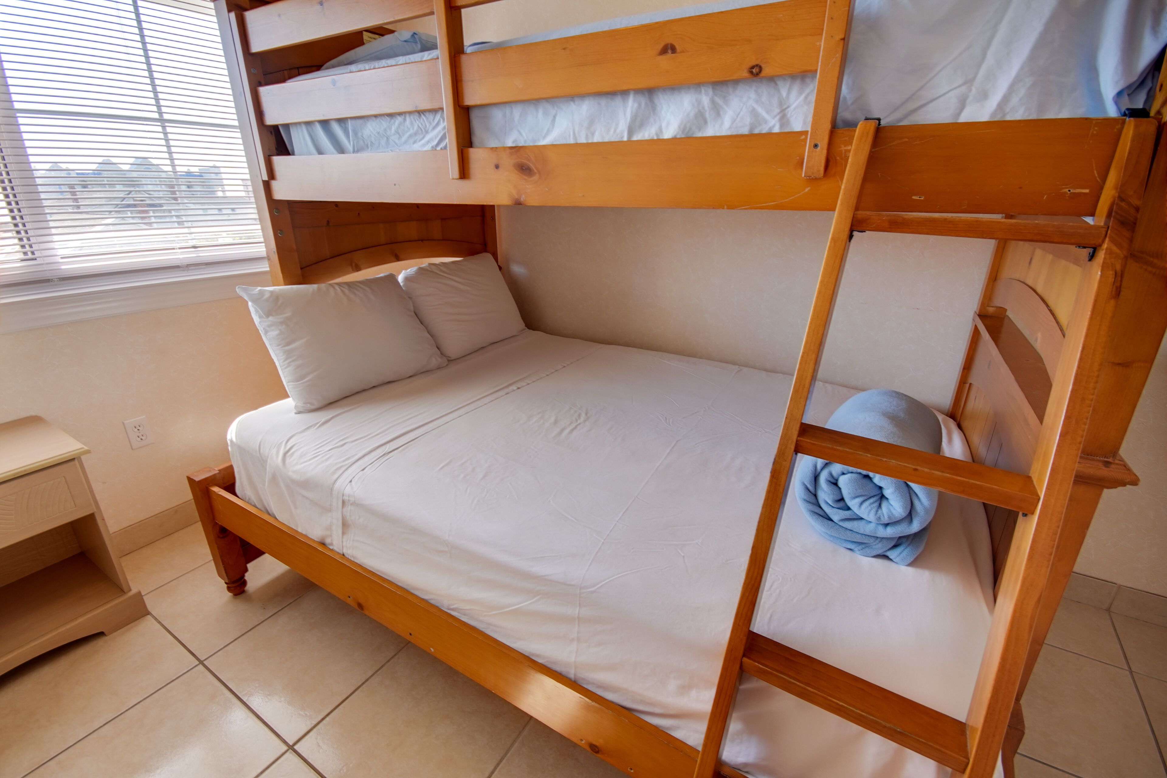 A bunk bed with a wooden frame and white bedding.