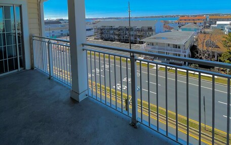 A balcony with a view of a parking lot and buildings.
