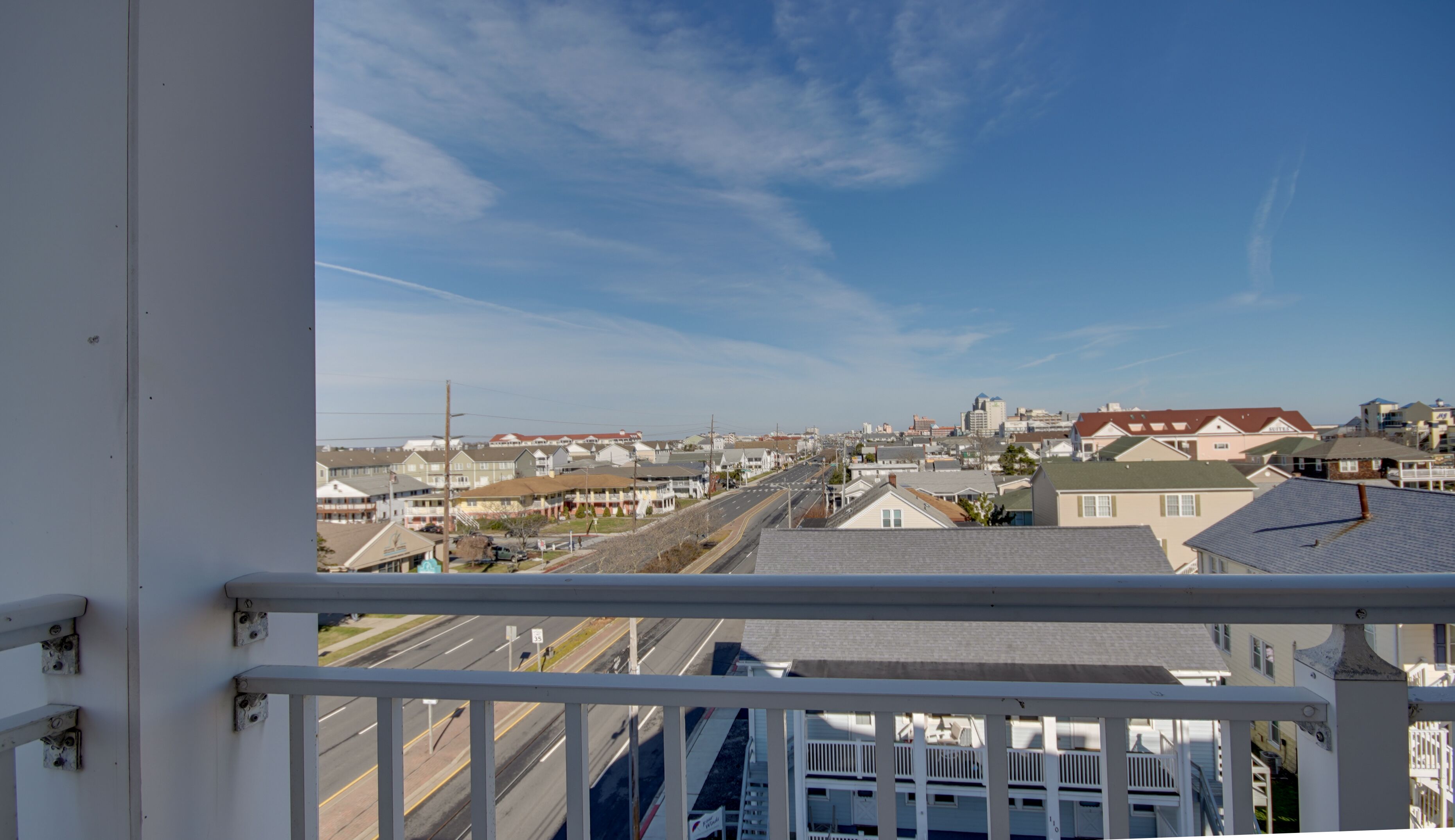 A balcony with a view of a residential area, including houses and a road.