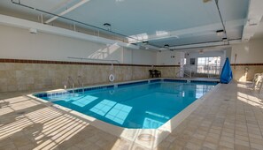 An indoor swimming pool with clear blue water, tiled walls, and a tiled floor. - Americana Condos 10th street (Ocean City)