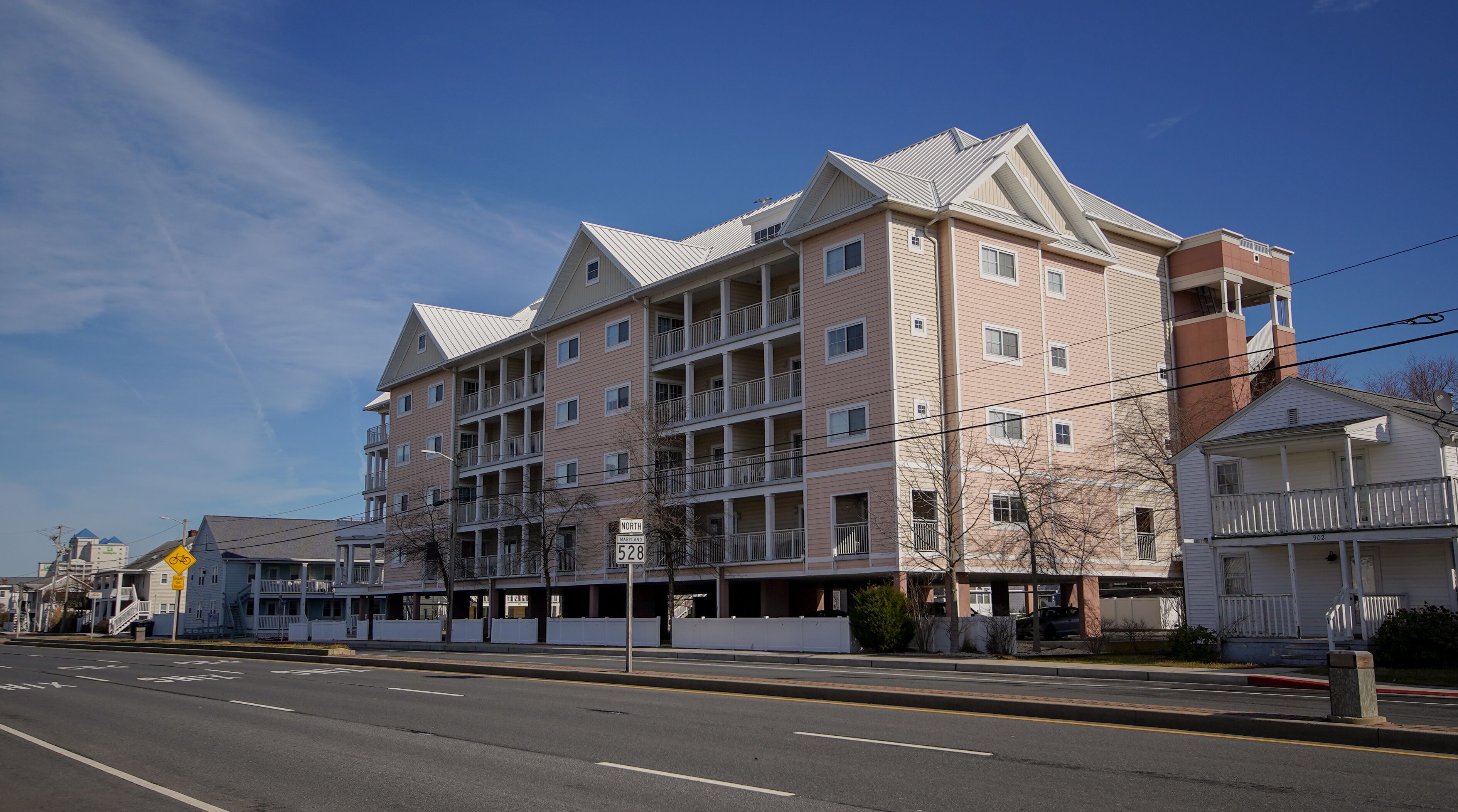 A multi-story hotel with balconies, a clear sky, and a road in the foreground.