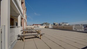 A rooftop terrace with picnic tables and a white railing. - Americana Condos 10th street (Ocean City)