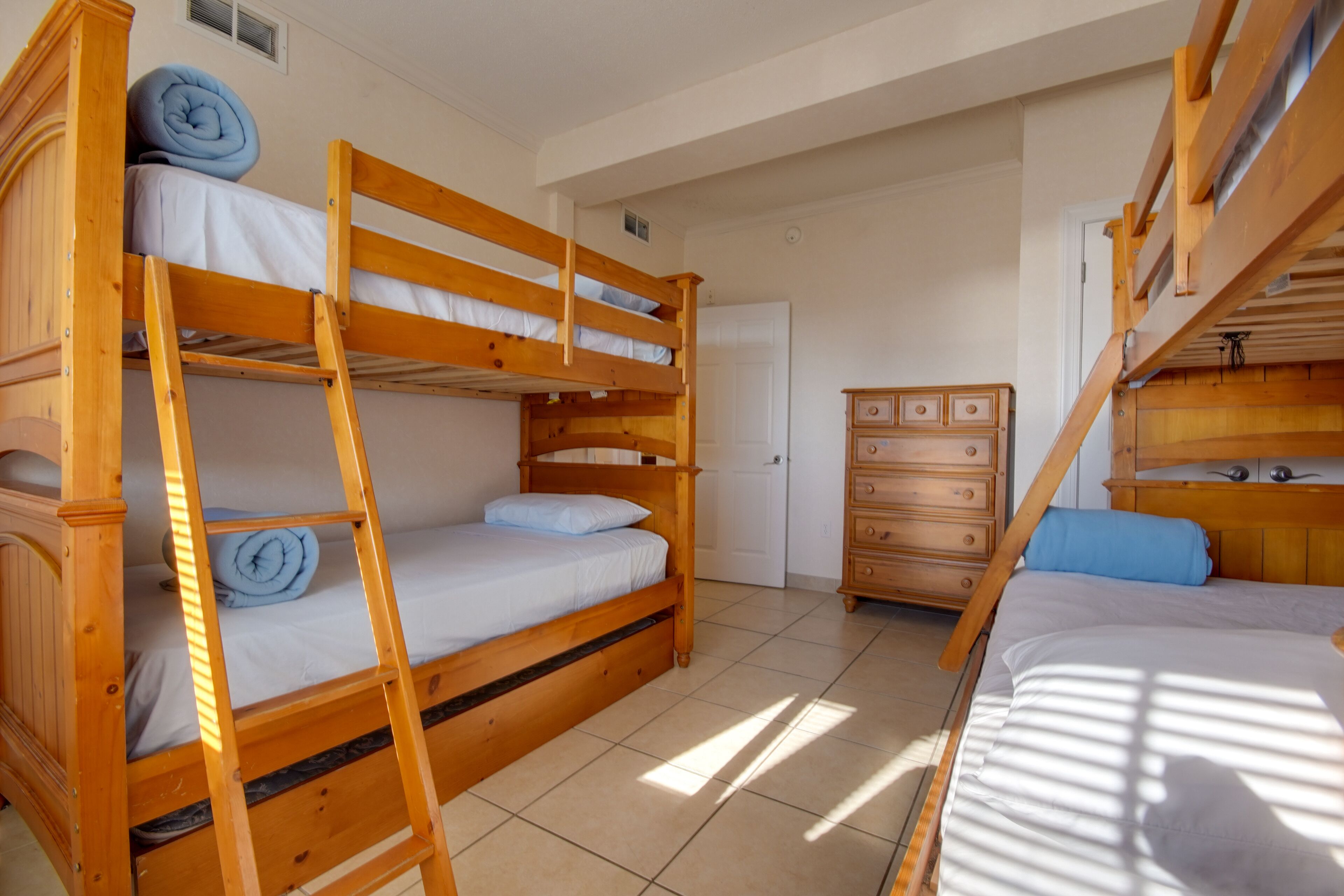 A room with two bunk beds, a wooden dresser, and a door.