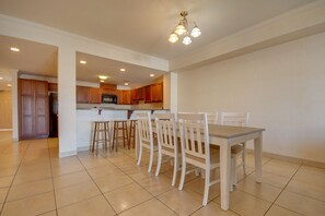 A spacious kitchen with wooden cabinets, a central island, and a dining area with a table and chairs. - Americana Condos 10th street (Ocean City)