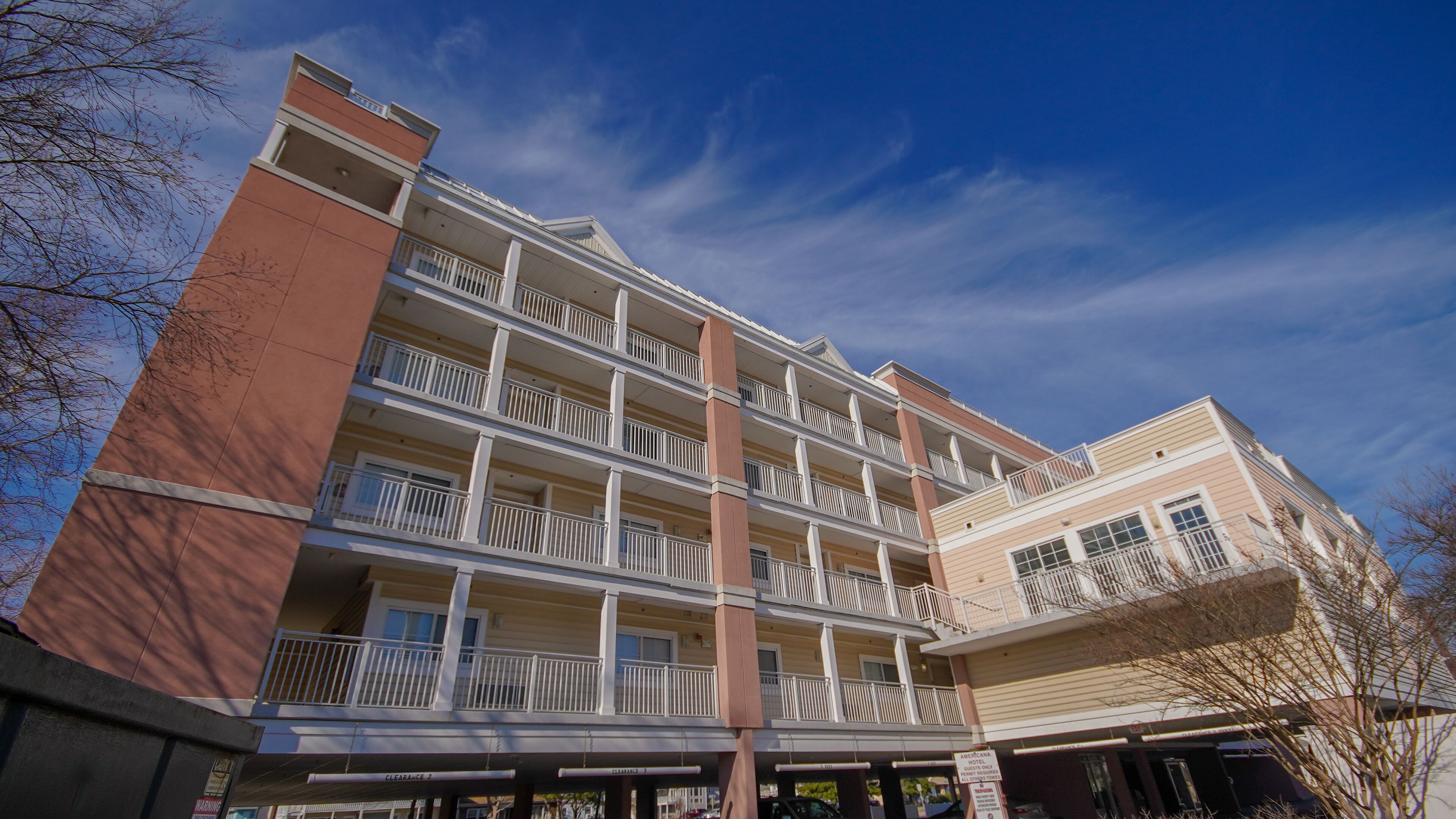 Un hotel a più piani con balconi, un garage e cielo sereno.