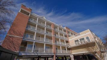 A multi-story hotel with balconies, a garage, and a clear sky.