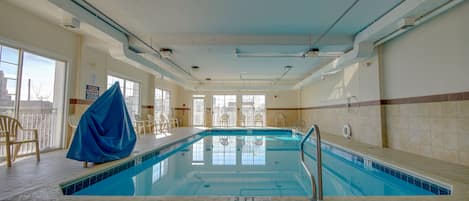Piscina interior con agua cristalina, una marca de profundidad de 0,9 metros y un área techada con sillas.