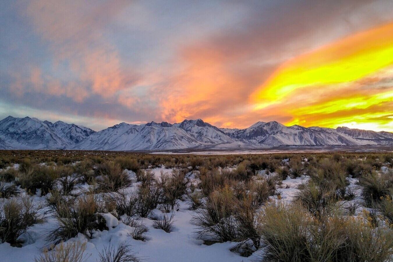 A snowy mountain range with a sunset.