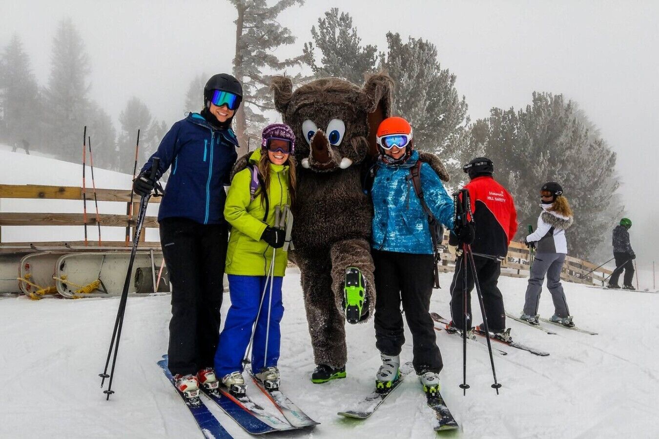 A snowy ski slope with skiers and a mascot.