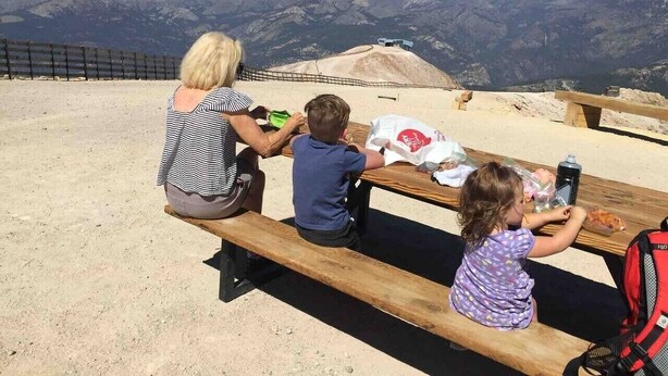 A family of three at a picnic table with a scenic mountain view in the background. - EV Charging. Private garage in town by restaurants (Mammoth Lakes)