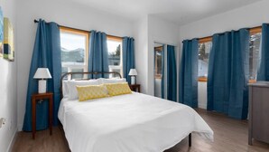 A bedroom with a bed, two bedside tables, a nightstand, and a window with curtains. - EV Charging. Private garage in town by restaurants (Mammoth Lakes)