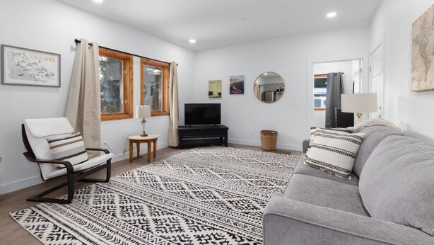 A living room with a sofa, a chair, a TV, a rug, and a window with curtains.