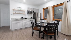 A modern kitchen with white cabinets, a built-in microwave, and a dining table set for four.