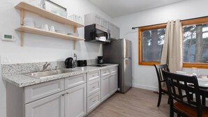 A kitchen with a granite countertop, stainless steel appliances, and a dining area with a table and chairs.