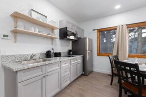 Een keuken met een granieten aanrecht, roestvrijstalen apparatuur en een eethoek met een tafel en stoelen.