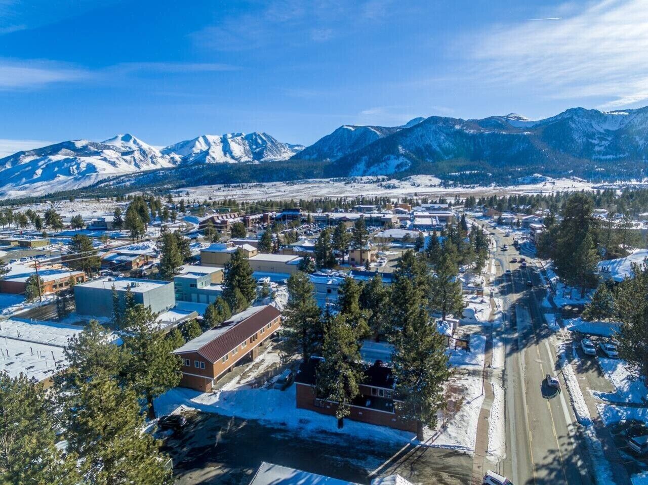 A town with buildings, roads, and snow-covered mountains in the background.